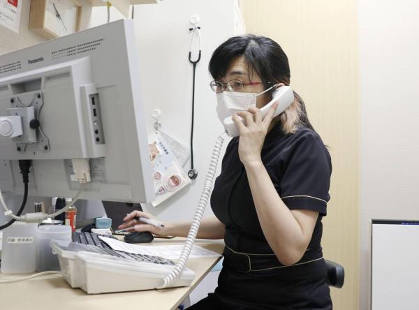 A doctor checks on a COVID-19 patient recuperating at home in Tokyo in February. | KYODO
