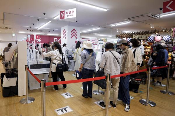 Customers wait in line for self-service checkout kiosks at Daiso Industries Co.'s global flagship store in the Ginza district of Tokyo on Tuesday. | BLOOMBERG